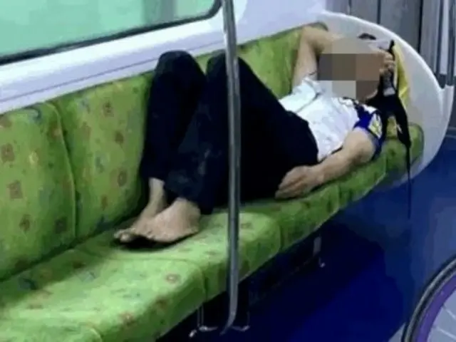 ชายชาวเกาหลีใต้นอนเท้าเปล่าขณะนั่งเก้าอี้ 4 ที่นั่งบนรถไฟใต้ดิน